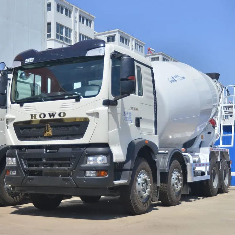 Front three-quarter view of the Howo TX 8×4 Concrete Mixer Truck highlighting the mixing drum, cab, and durable chassis on a construction site. Front three-quarter view of the Howo TX 8×4 Concrete Mixer Truck highlighting the mixing drum, cab, and durable chassis on a construction site.