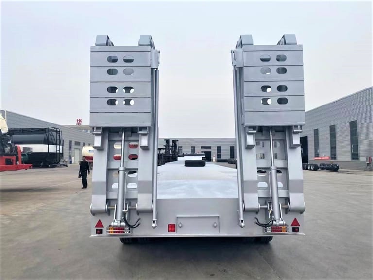 Rear view of ZW Group 4 Axle 100 Ton Lowbed Semi Trailer showing spring ramps, reinforced rear frame, and 16 heavy-duty tires for safe heavy machinery transport.