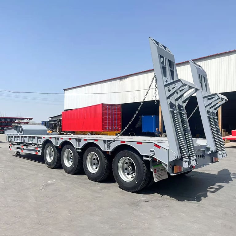 Rear three-quarter view of 80 ton lowbed semi trailer showing spring-loaded ramps and reinforced rear frame for safe loading of heavy equipment. Rear three-quarter view of 80 ton lowbed semi trailer showing spring-loaded ramps and reinforced rear frame for safe loading of heavy equipment.