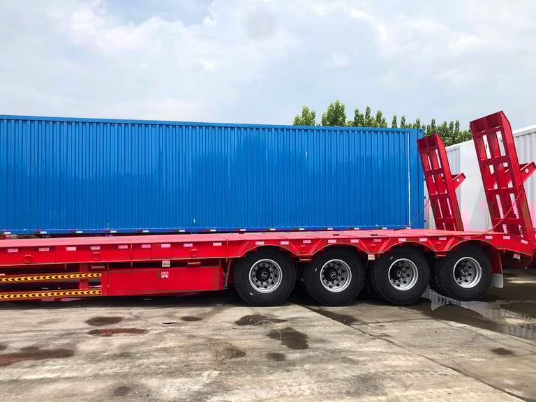 Side view of ZW Group 4 Axle 100 Ton Lowbed Semi Trailer showing long low-deck, mechanical suspension, and robust axles for heavy equipment transport. Side view of ZW Group 4 Axle 100 Ton Lowbed Semi Trailer showing long low-deck, mechanical suspension, and robust axles for heavy equipment transport.