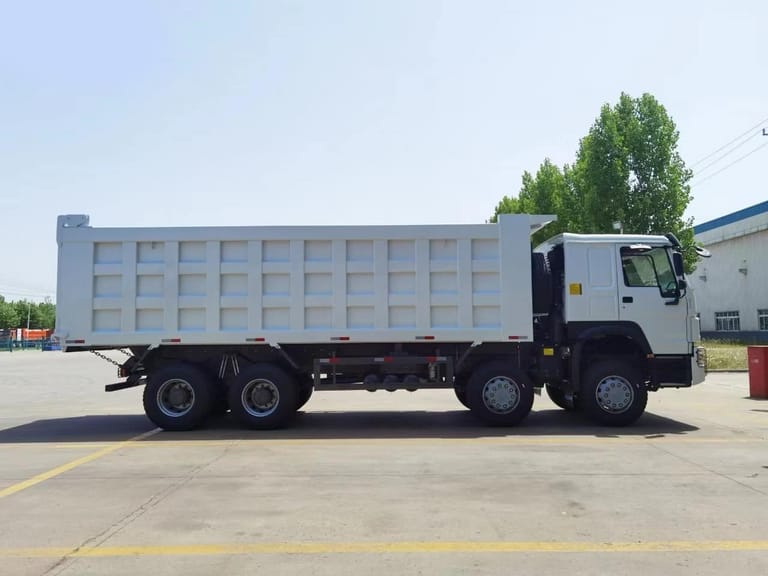 Side view of HOWO 380HP 8x4 dump truck showing reinforced body, 8x4 drivetrain, and large-capacity cargo bed for mining and construction transport