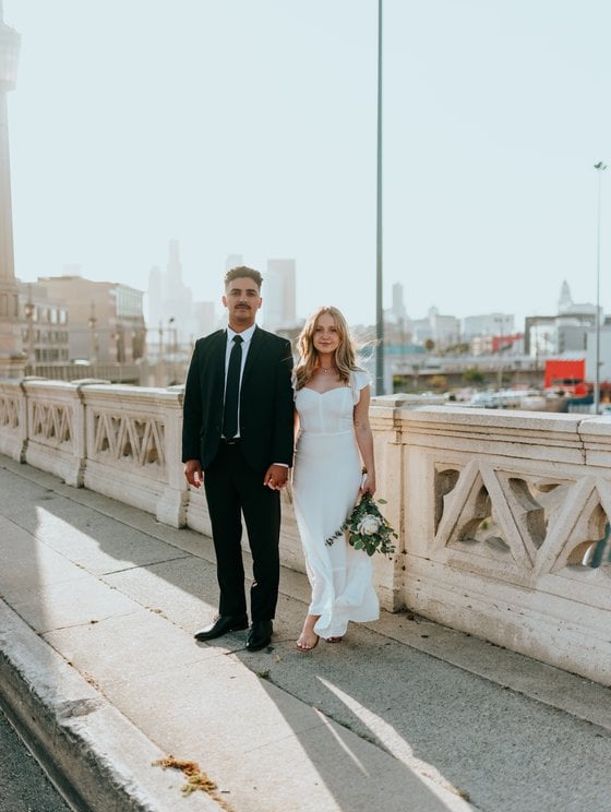 man in black suit standing beside woman in white wedding dress