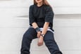customer in black long sleeve shirt and blue denim jeans sitting on white concrete wall
