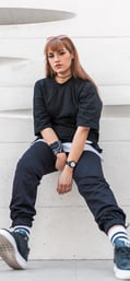 woman in black long sleeve shirt and blue denim jeans sitting on white concrete wall