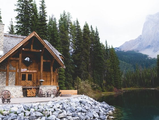 brown wooden house near lake surrounded by green trees during daytime