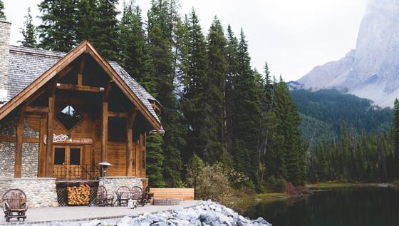 brown wooden house near lake surrounded by green trees during daytime