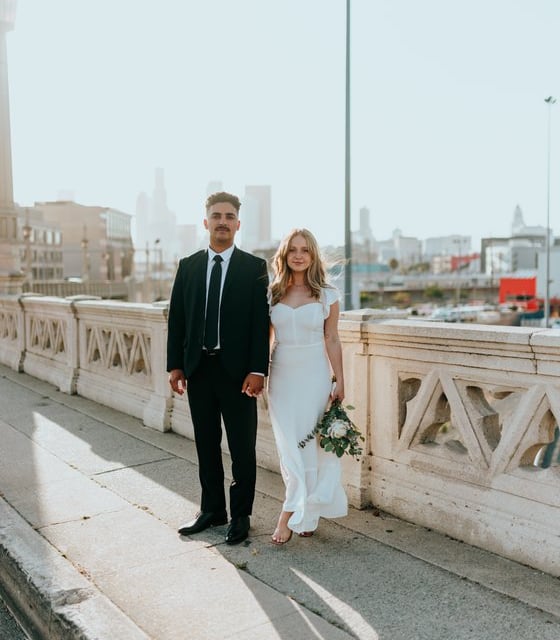 man in black suit standing beside woman in white wedding dress