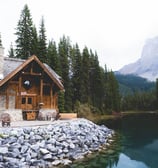 brown wooden house near lake surrounded by green trees during daytime
