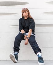 woman in black long sleeve shirt and blue denim jeans sitting on white concrete wall