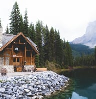 brown wooden house near lake surrounded by green trees during daytime
