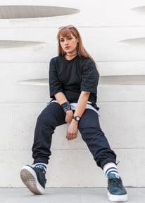 woman in black long sleeve shirt and blue denim jeans sitting on white concrete wall