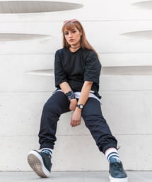woman in black long sleeve shirt and blue denim jeans sitting on white concrete wall