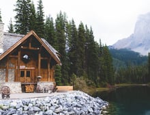 brown wooden house near lake surrounded by green trees during daytime