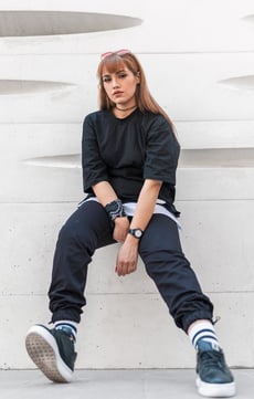 woman in black long sleeve shirt and blue denim jeans sitting on white concrete wall