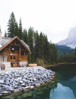 brown wooden house near lake surrounded by green trees during daytime