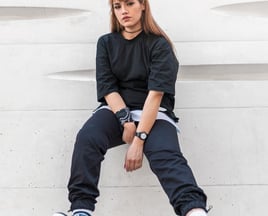 woman in black long sleeve shirt and blue denim jeans sitting on white concrete wall