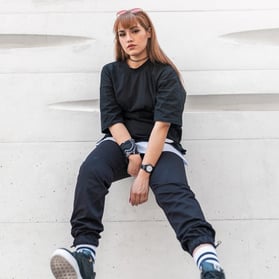 woman in black long sleeve shirt and blue denim jeans sitting on white concrete wall