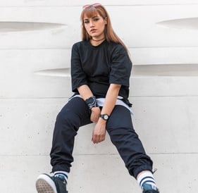 woman in black long sleeve shirt and blue denim jeans sitting on white concrete wall