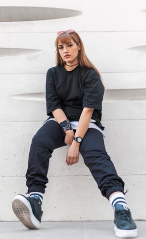 woman in black long sleeve shirt and blue denim jeans sitting on white concrete wall