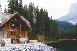 brown wooden house near lake surrounded by green trees during daytime