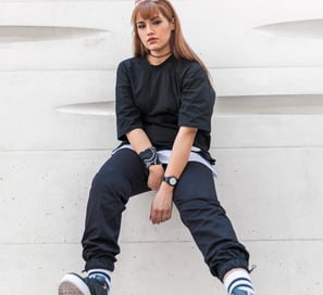 woman in black long sleeve shirt and blue denim jeans sitting on white concrete wall