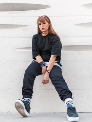 woman in black long sleeve shirt and blue denim jeans sitting on white concrete wall