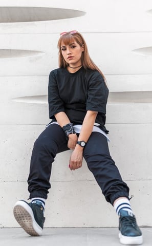 woman in black long sleeve shirt and blue denim jeans sitting on white concrete wall