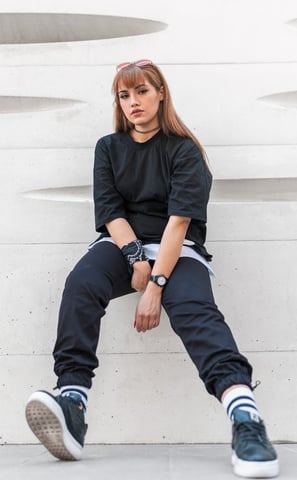 woman in black long sleeve shirt and blue denim jeans sitting on white concrete wall