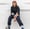 woman in black long sleeve shirt and blue denim jeans sitting on white concrete wall