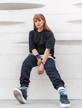 woman in black long sleeve shirt and blue denim jeans sitting on white concrete wall
