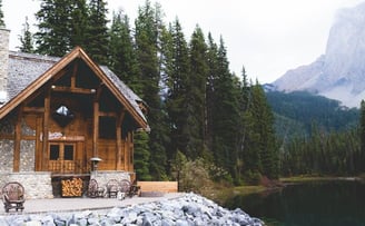 brown wooden house near lake surrounded by green trees during daytime