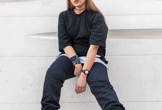 woman in black long sleeve shirt and blue denim jeans sitting on white concrete wall