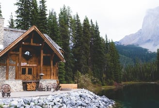 brown wooden house near lake surrounded by green trees during daytime