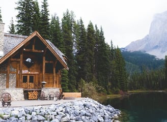 brown wooden house near lake surrounded by green trees during daytime