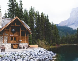 brown wooden house near lake surrounded by green trees during daytime