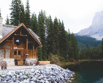 brown wooden house near lake surrounded by green trees during daytime