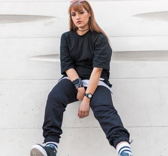 woman in black long sleeve shirt and blue denim jeans sitting on white concrete wall
