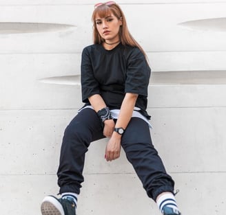 woman in black long sleeve shirt and blue denim jeans sitting on white concrete wall