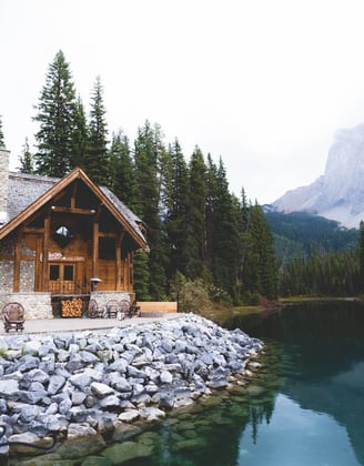brown wooden house near lake surrounded by green trees during daytime