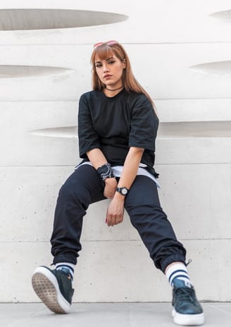 woman in black long sleeve shirt and blue denim jeans sitting on white concrete wall