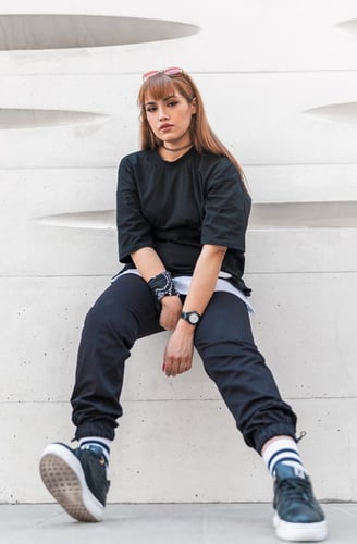 woman in black long sleeve shirt and blue denim jeans sitting on white concrete wall