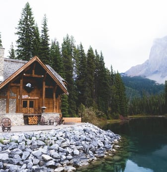 brown wooden house near lake surrounded by green trees during daytime