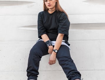 woman in black long sleeve shirt and blue denim jeans sitting on white concrete wall