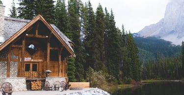 brown wooden house near lake surrounded by green trees during daytime
