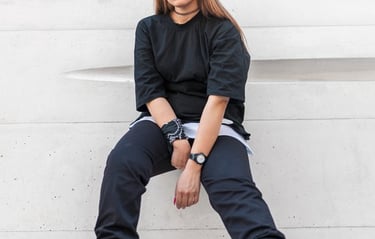 woman in black long sleeve shirt and blue denim jeans sitting on white concrete wall