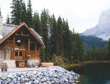 brown wooden house near lake surrounded by green trees during daytime