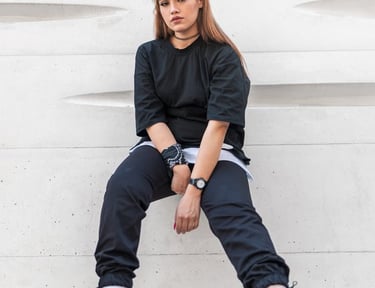 woman in black long sleeve shirt and blue denim jeans sitting on white concrete wall