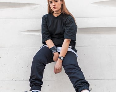 woman in black long sleeve shirt and blue denim jeans sitting on white concrete wall