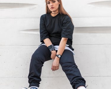 woman in black long sleeve shirt and blue denim jeans sitting on white concrete wall