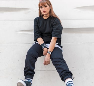 woman in black long sleeve shirt and blue denim jeans sitting on white concrete wall